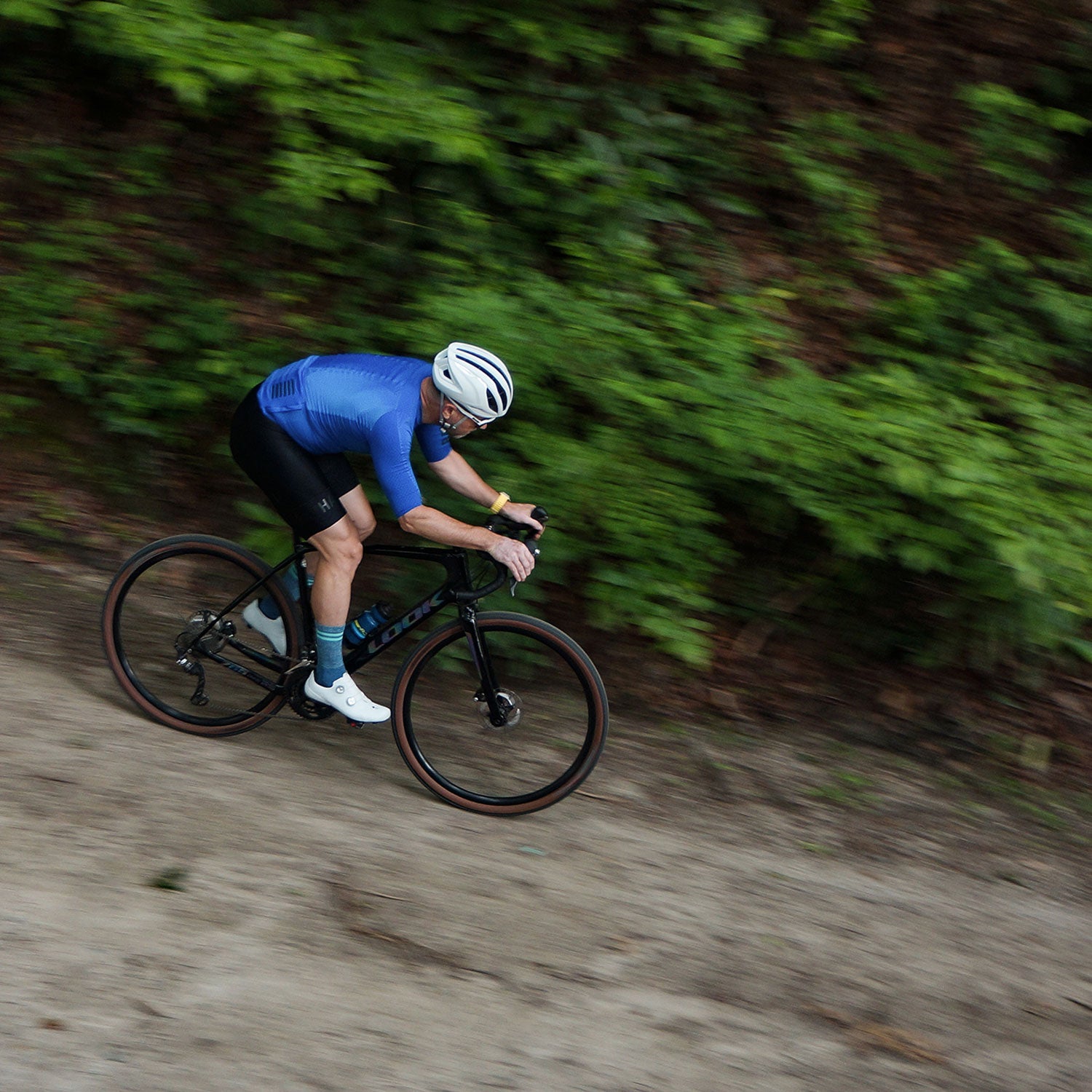 Cyclist riding down gravel road wearing DeFeet Cyclismo padded cycling socks