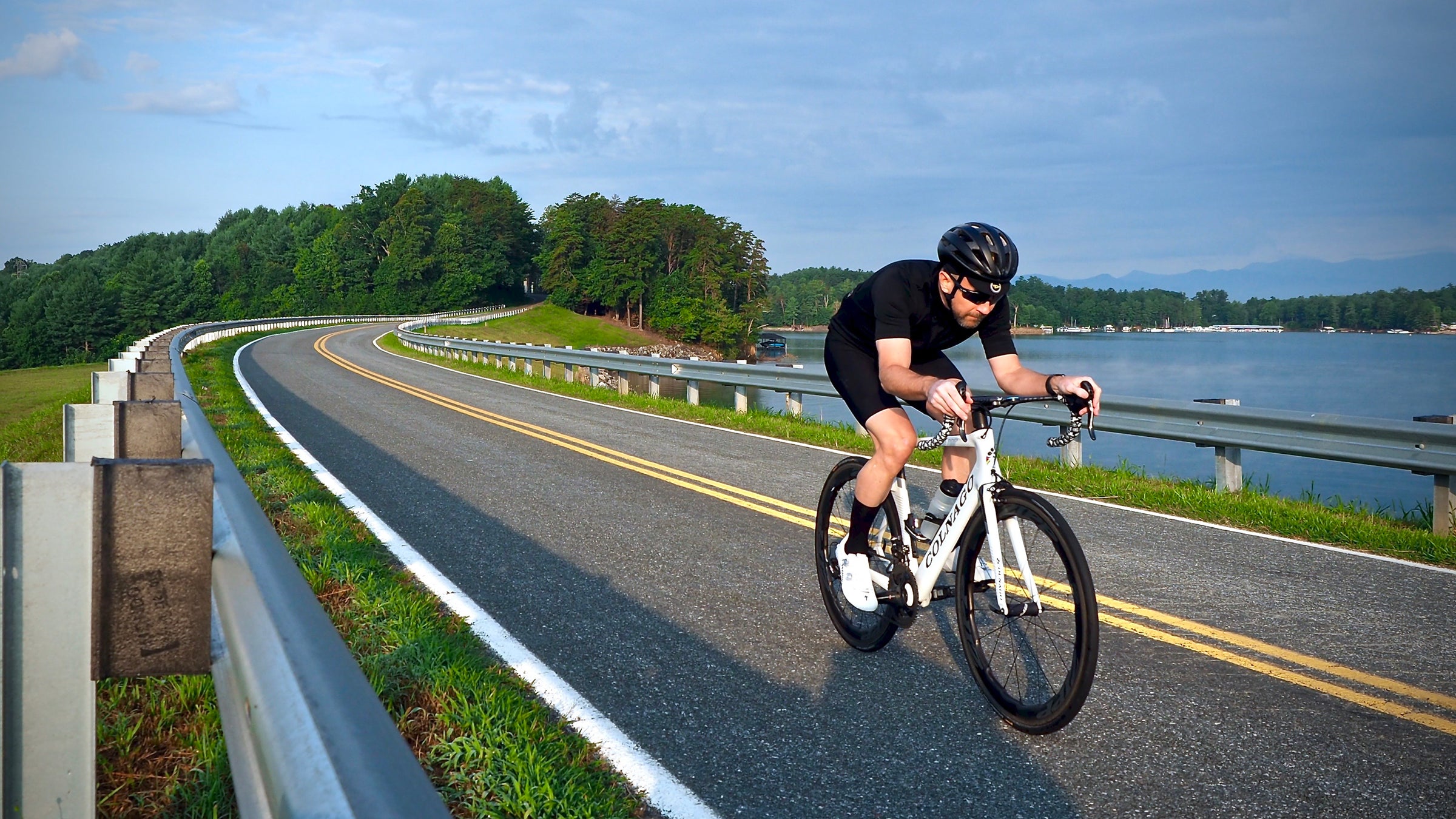 Cyclist wearing DeFeet Aireator cycling socks while riding on a waterfront stretch of asphalt roadway